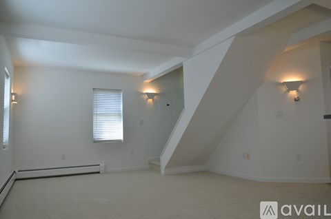 A spacious room with a staircase leading to the upper level.