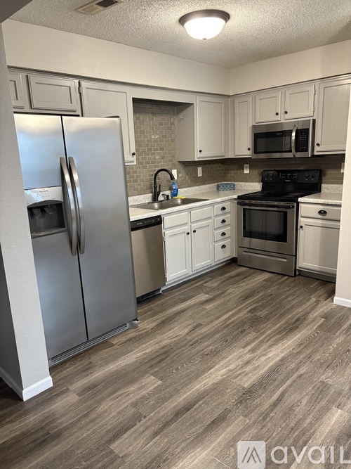 A kitchen with a refrigerator, oven, and microwave.