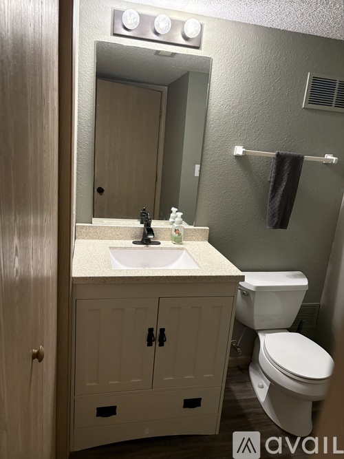 A bathroom with a toilet, sink, and mirror.