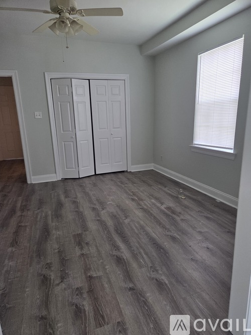 A room with a ceiling fan and a window with blinds.