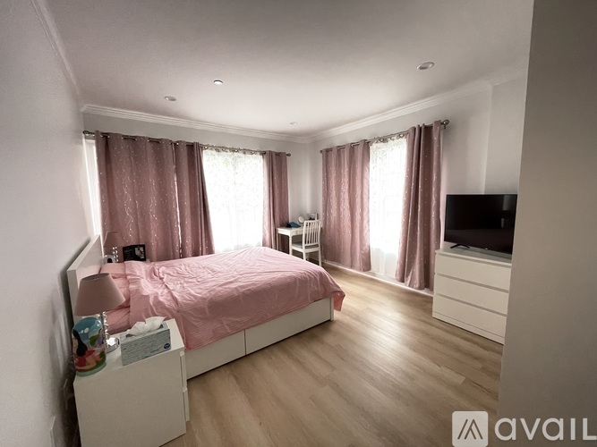 A bedroom with a bed, nightstand, and television.