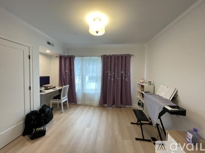 A room with a desk, chair, and a piano.
