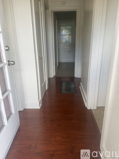 A hallway with white walls and wood flooring.