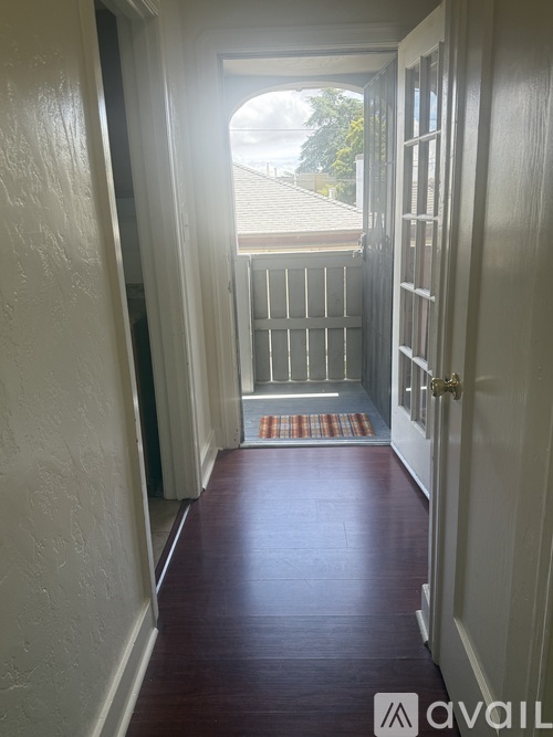 A hallway with a red carpet leading to a door.