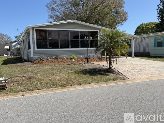 A grey house with a white fence and a tree in front.