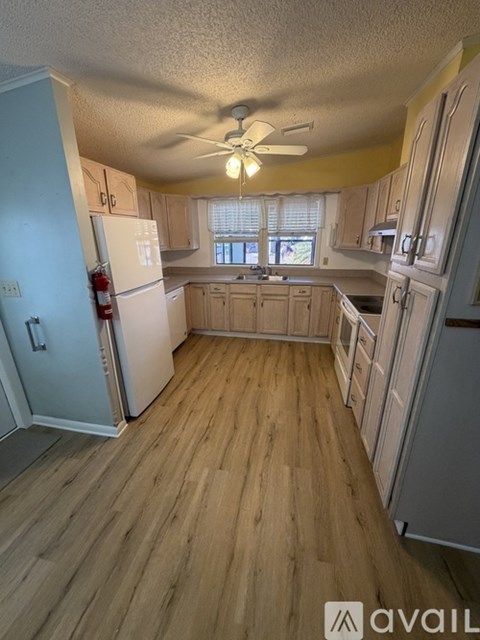 A kitchen with wooden floors and a ceiling fan.
