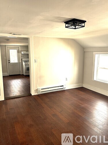 A room with wooden floors and a window letting in sunlight.