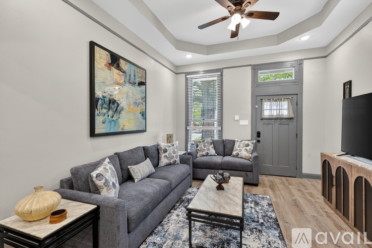 A living room with a grey couch, a coffee table, and a painting on the wall.
