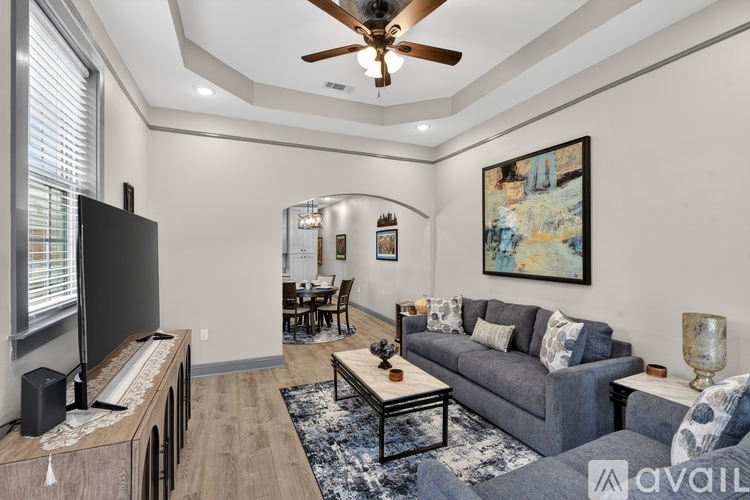 A living room with a grey couch, a wooden table, and a ceiling fan.