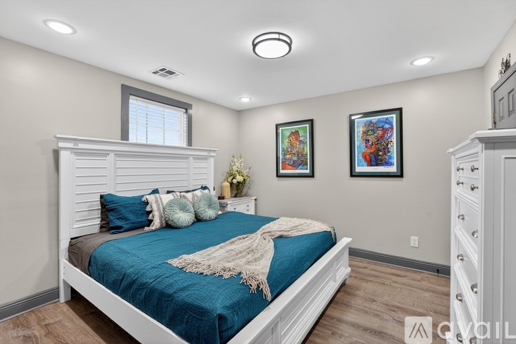 A bedroom with a bed, dresser, and two pictures on the wall.