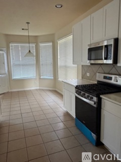 A kitchen with white cabinets and a black stove top oven.