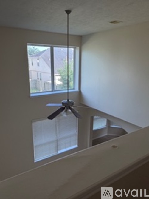 A room with a ceiling fan and a window.