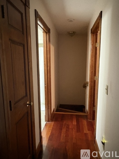 A hallway with wooden floors and white walls.