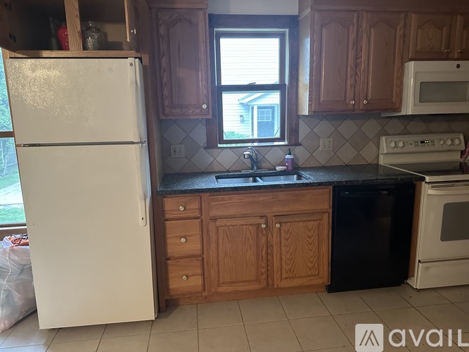 A kitchen with a white refrigerator, wooden cabinets, and a black dishwasher.
