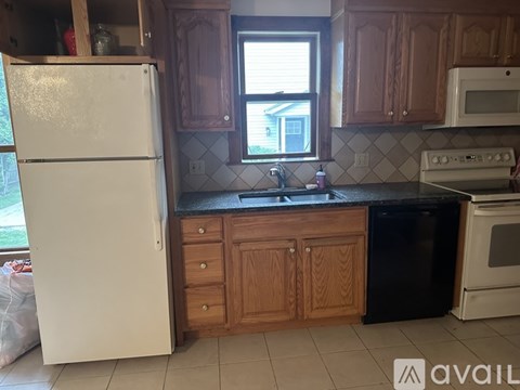 A kitchen with a white refrigerator, wooden cabinets, and a black dishwasher.