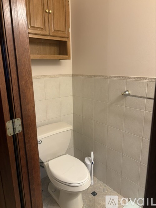 A white toilet in a small bathroom with a wooden door.