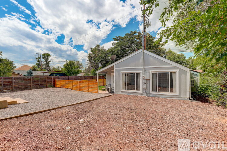 A backyard with a gravel area and a small house.