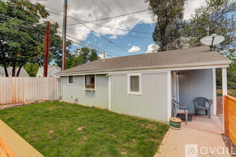 A small house with a grey roof and a white fence.