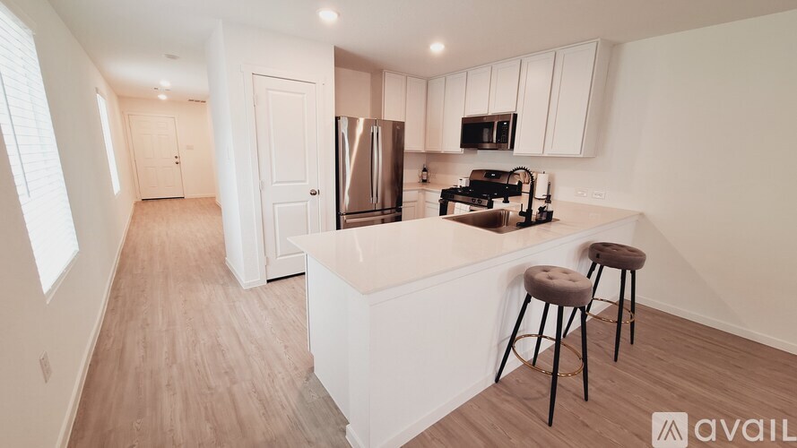 A kitchen with white cabinets and a white island with two stools.