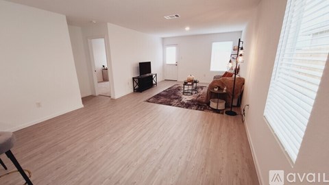 A living room with a brown rug and a wooden floor.