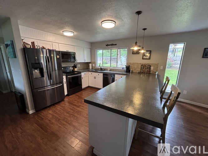 A kitchen with a black countertop and wooden floors.