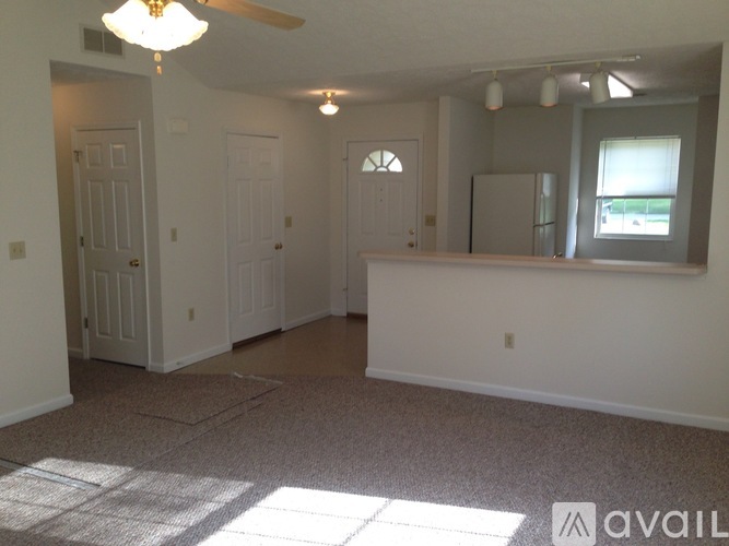 A room with a carpeted floor and a ceiling fan.