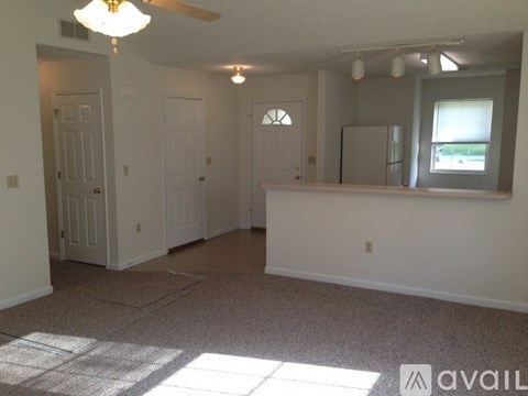 A room with a carpeted floor and a ceiling fan.