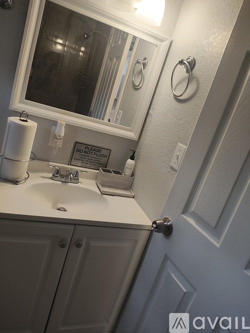 A bathroom sink with a mirror above it and a sign on the mirror.
