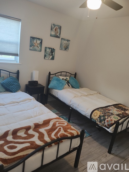 A bedroom with two beds and a ceiling fan.