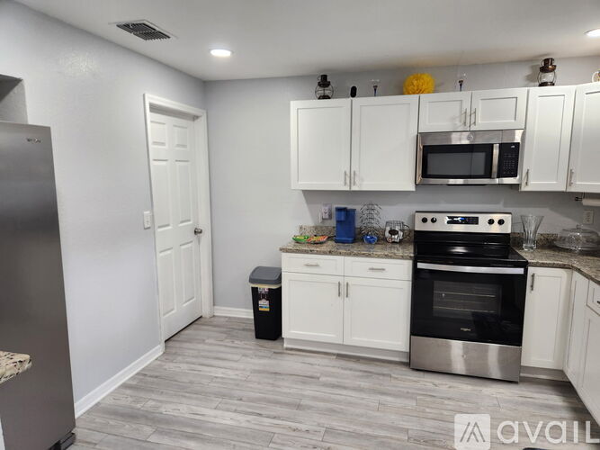 A kitchen with white cabinets and a stainless steel refrigerator.