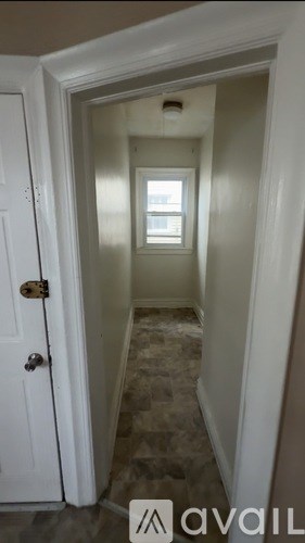 A hallway with a door on the left and a window on the right.