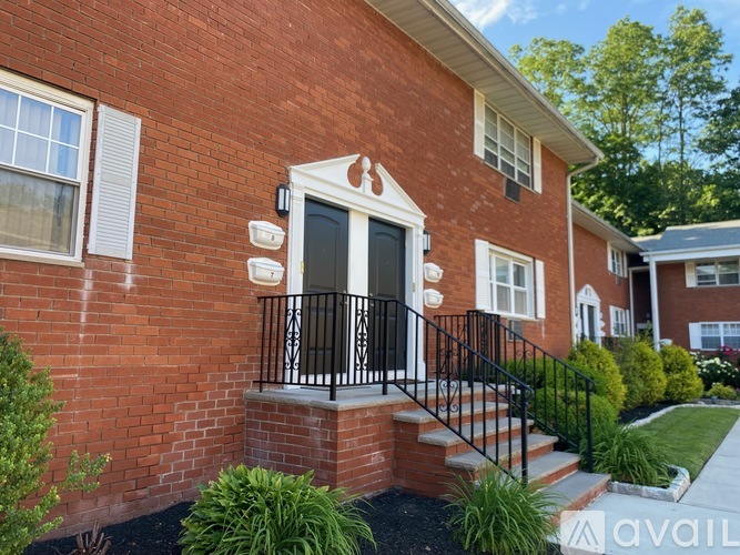 A red brick house with a black iron railing on the front porch.