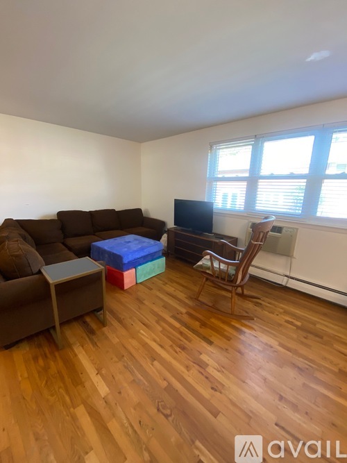 A living room with a brown couch, a small table, a chair, and a television.