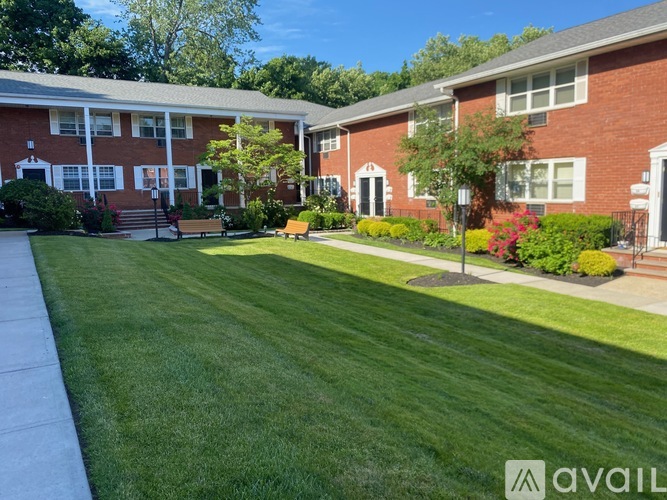 A grassy area in front of a brick building with a bench.