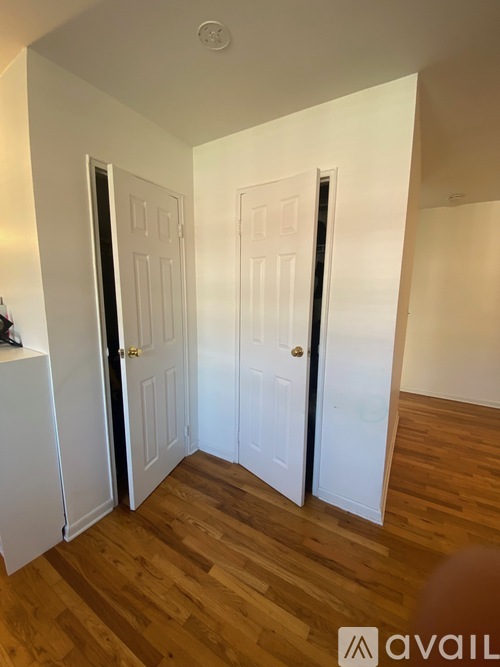 A room with two white doors and wooden flooring.