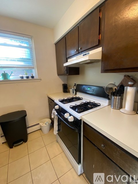 A kitchen with a black stove top oven and a window with blinds.