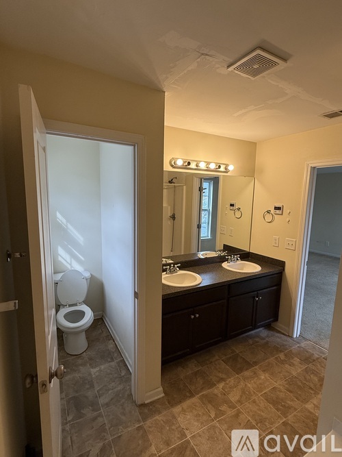 A bathroom with a toilet, sink, and mirror.