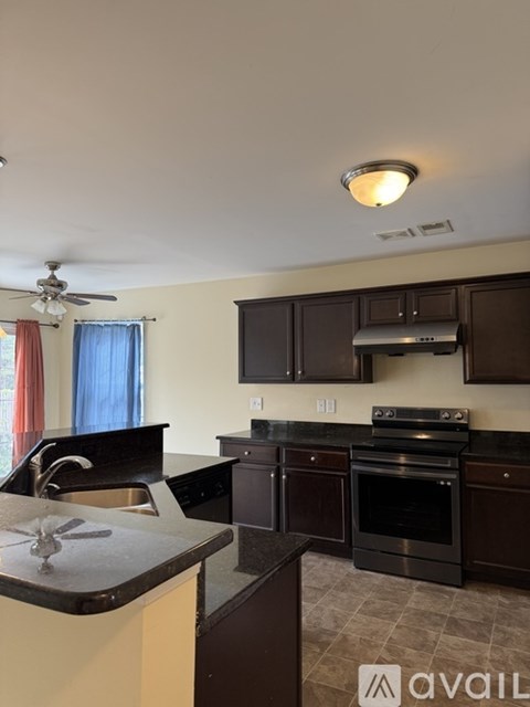 A kitchen with dark brown cabinets and a black stove top oven.