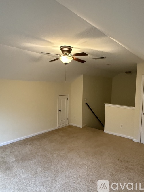 A room with a ceiling fan and carpeted floor.
