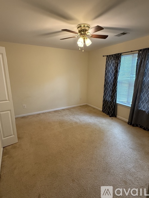 A room with a ceiling fan and carpeted floor.