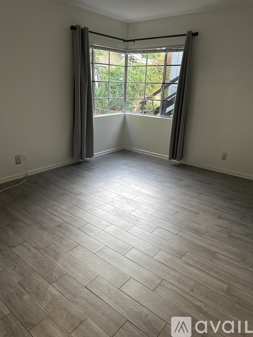 A room with a large window and wooden flooring.