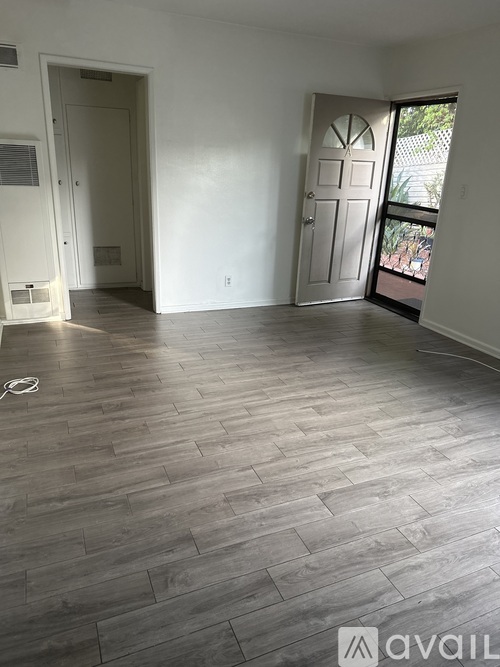 A room with wooden flooring and a door leading outside.