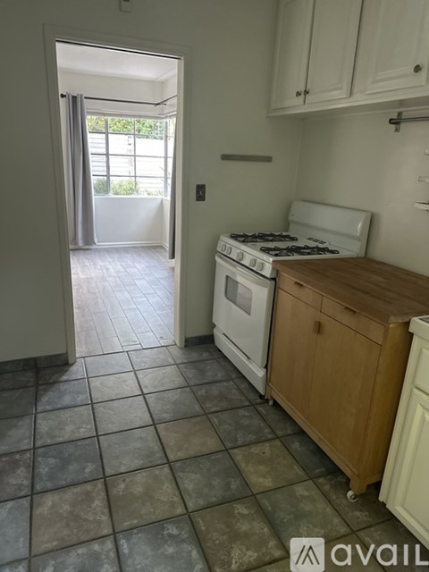 A kitchen with a stove and a doorway leading to a balcony.