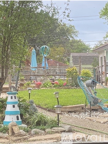 A garden with a blue and white striped lighthouse and a green chair.