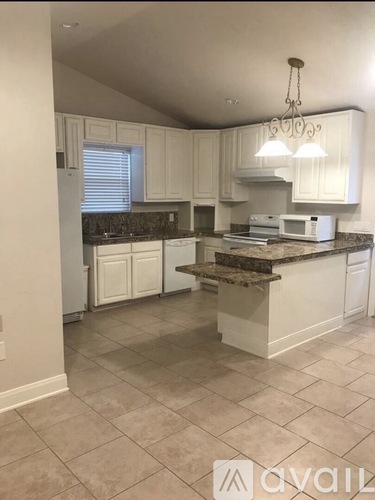 A kitchen with white cabinets and a granite countertop.