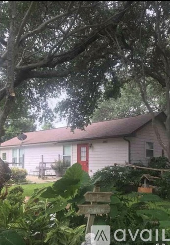 A house with a red door is surrounded by greenery.