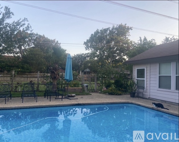 A pool with a blue umbrella and a house in the background.