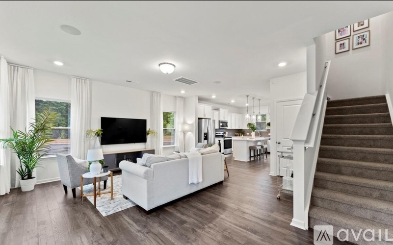 A living room with a white sofa and a staircase.