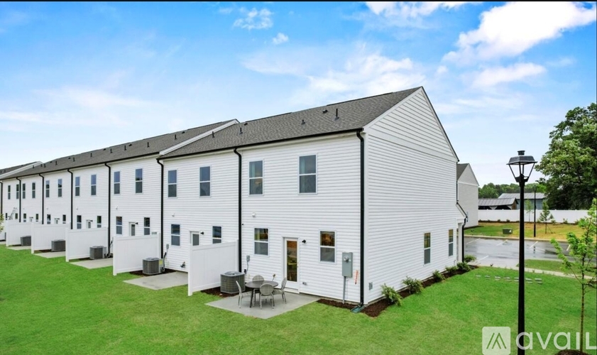 A row of white houses with a green lawn in front.