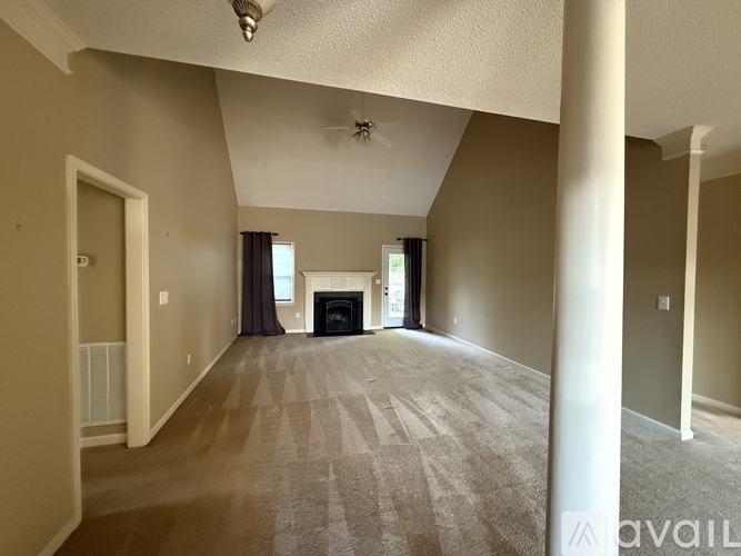 A spacious living room with a fireplace and a carpeted floor.